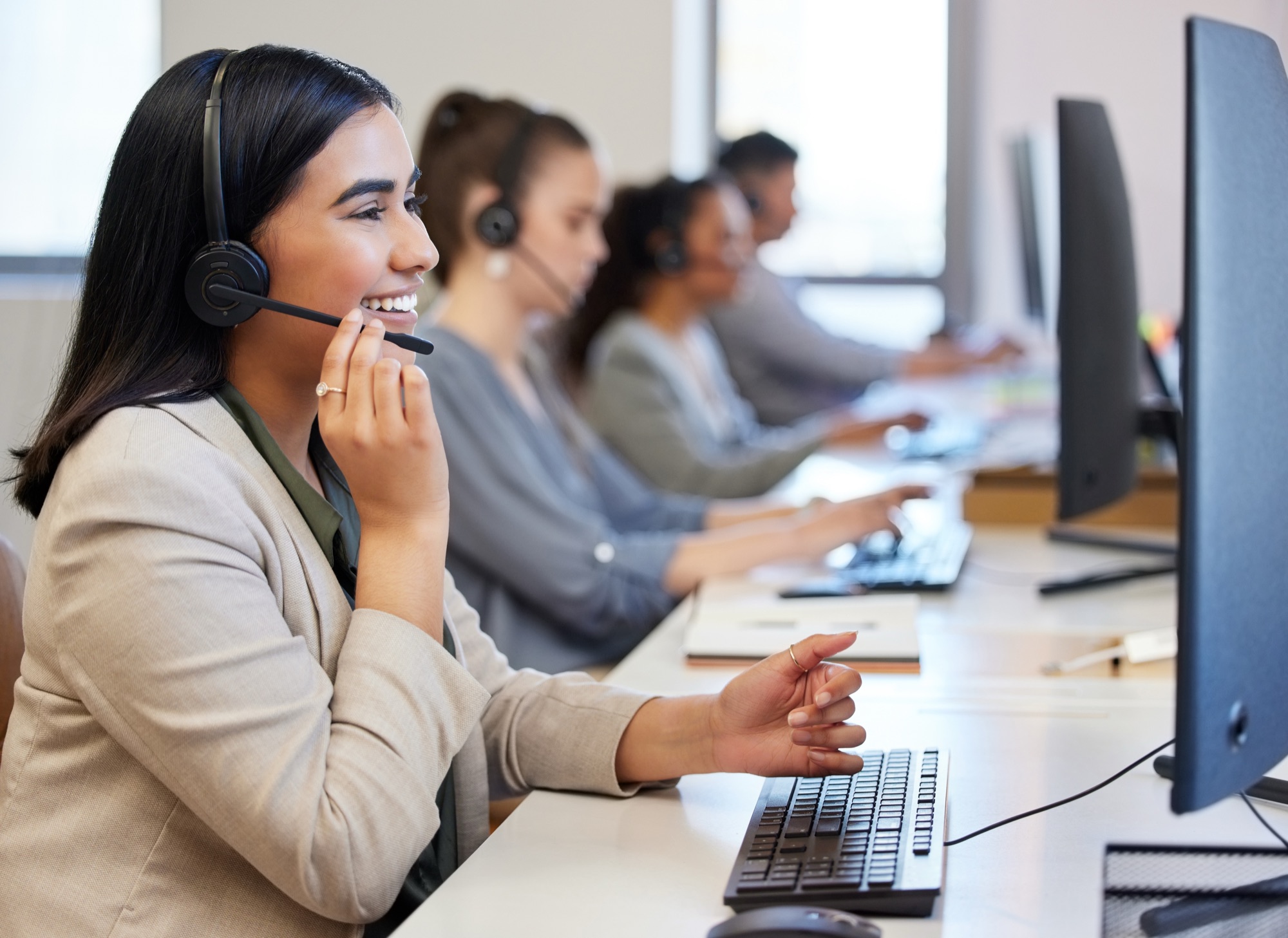 A smiling AMAC member services representative taking a call at her desk